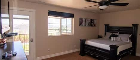 Queen bed in main room shows balcony access, view of the Tacit Shadow yard.