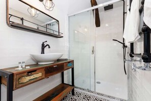 A clean, modern bathroom with a glass-enclosed shower and white walls. It has a sleek and functional design with ample space.