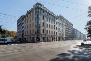 A street view of a large, historic-looking building with a classical facade. The architecture features large windows and ornate detailing.