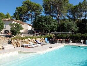 Tonnelle, salon de jardin et transats au bord de la piscine