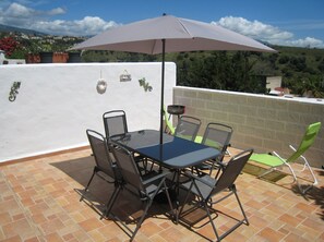 Back patio with table, chairs and sunbeds.