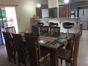 Dining table, breakfast bar, kitchen and access to the covered terrace/ pool