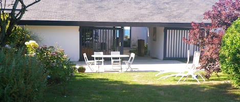 Vue côté sud prise, du jardin,  de la terrasse, du patio et, au fond, de la mer.