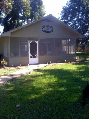 Screened porch with swing and two rocking chairs and a table and chairs.