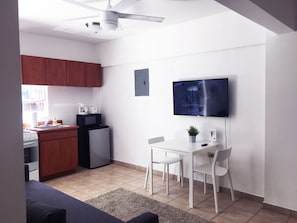 Area de comedor con 2 sillas, smart TV y esta proximo al area de cocina.