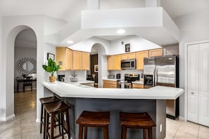 Open concept kitchen with modern appliances and breakfast bar seating for 4