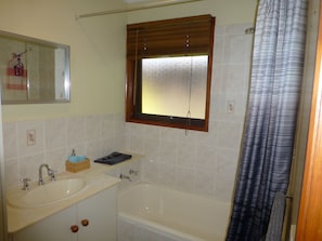 Main Bathroom with shower over bath with hand soap and body wash 