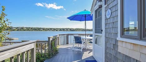 porch overlooking cove with table, chairs and umbrella and view of cove