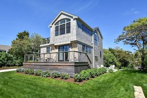 front view of home. Big porch on first floor. large arched windows on second floor. Green grass surrounding front and lower right