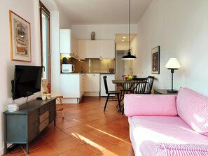 The living room features a comfortable sofa, ideal for relaxing after a day of exploring Barcelona. The open layout allows for a seamless flow between the living space and the fully equipped kitchen, perfect for preparing meals at home.  The apartment is 