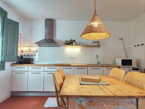 The kitchen features a modern design with white cabinets, a stainless steel range hood, and a wooden countertop. A small breakfast nook can be found to the right of the kitchen, with a wooden table and chairs, perfect for enjoying a simple meal or morning