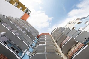 A view looking up at the building's modern facade, with balconies arranged in a geometric pattern.