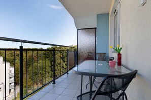 A small balcony with a table and chairs, overlooking neighboring buildings. Perfect for relaxing with a view.