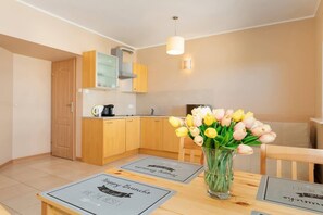  A table set for two with white tableware and a vase of flowers. Light walls and plenty of natural light make it feel cozy.