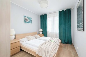 A cozy bedroom with a double bed, green curtains, and access to a private balcony.