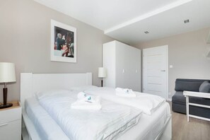 A bedroom featuring a double bed with white bedding, bedside lamps, and minimal decor, creating a peaceful ambiance.