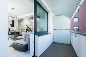 A balcony with chairs and a small table, overlooking an outdoor view, offering a peaceful space to relax.