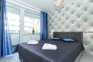 A bedroom featuring a bed with a padded headboard, blue curtains, and clean decor, providing a cozy and relaxing atmosphere.