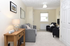 A comfortable living area with sofa and chairs, widescreen TV with Netflix.