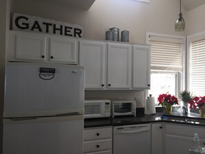 Clean,  stocked kitchen with gas stove, peninsula and large table with benches.