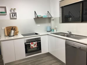 modern kitchen, dishwasher, oven and partially stocked pantry