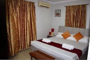 Bedroom with  two widow lamp,ac ,,side sitting bench,wardrobe,cushion,pillows.