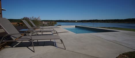 Expansive pool deck with 6 chaise lounges and outdoor dining