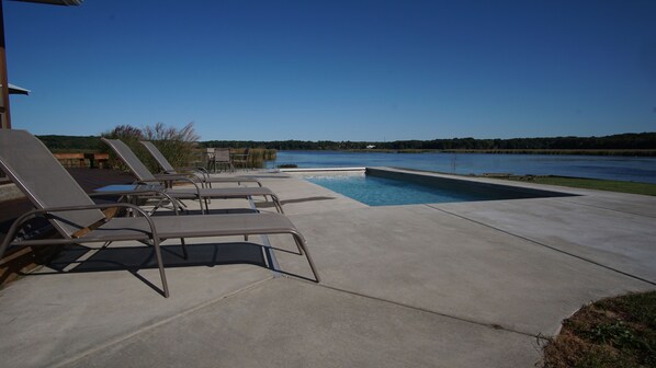 Expansive pool deck with 6 chaise lounges and outdoor dining