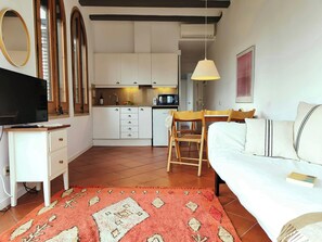 Living room with a sofa, dining table and an auxiliary table with TV. Open kitchen equipped with all its necessary tools, such as: a microwave, toaster, coffee maker.