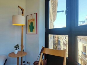 The apartment features large windows that offer breathtaking views of the bustling streets below.  Enjoy a moment of peace and observe the daily life of Barcelona from the comfort of your stylishly furnished living space. The view captures the unique char