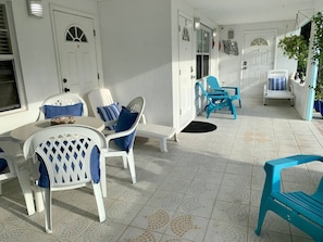 Front porch. Sun loungers. The blue deck chairs have been replaced with wooden benches.