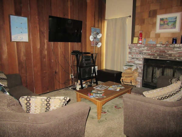 Living room includes fireplace, two couches, big screen tv.

