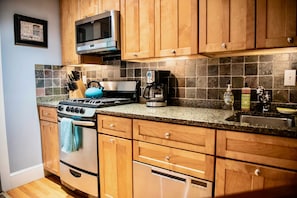 Fully stocked kitchen with stainless steel appliances, granite countertop.