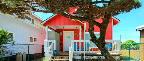 Front of house with fully fenced yard for kids & pups to play in & sunny deck.