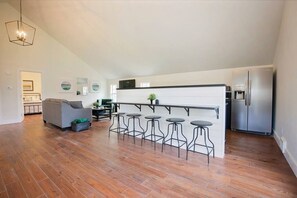 Spacious open-concept living area with bar seating, cozy lounge, and natural light.