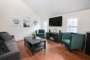 Stylish modern living room with cozy velvet chairs, smart TV, and natural light.
