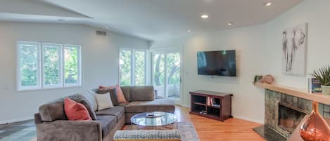 The living area features high ceilings, decorative fireplace, 55" TV with Cable 