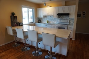 Spacious kitchen offers beautiful marble back splash and large quartz countertop
