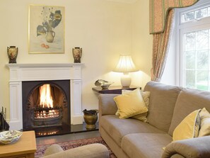There is a feature fireplace housing an open fire in the opulent living room | Tan Y Castell, Llanmill, near Narberth