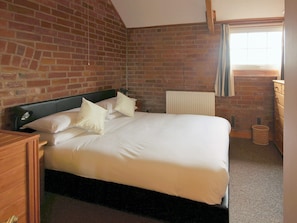 Double bedroom with exposed brick walls and sloping ceiling | Yarlington Mill - The Old Kennels Holidays, Ledbury