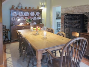 A grand farmhouse kitchen style table and a woodburning stove complement the traditional cottage furnishings | The Coach House - Berrington House, Tenbury Wells