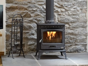 Warming wood burner in living room | Sgubor Ucha, Llanrhychwyn, Trefriw