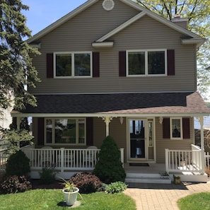 Front of home features covered porch and surrounded by beautiful garden