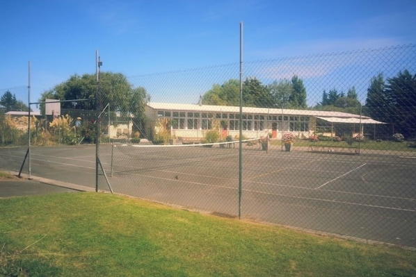 Looking across the tennis court to the school. The apartment is behind the tall birch tree
