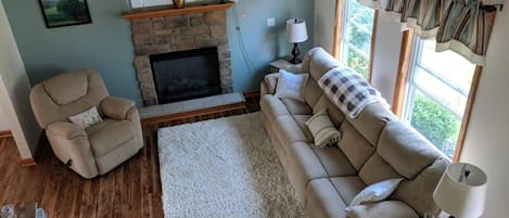 Enjoy this cozy living room with reclining  seating, electric fireplace, largeTV