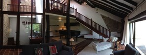Salón principal con gran ventanal, piano de cola y chimenea