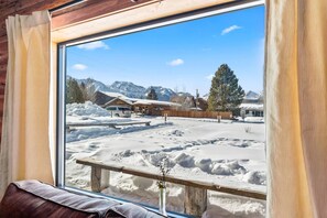Capture the breathtaking panorama of the Sawtooth Mountains through the expansive living room window, offering a picturesque vista that seamlessly blends with the cabin's natural surroundings.
