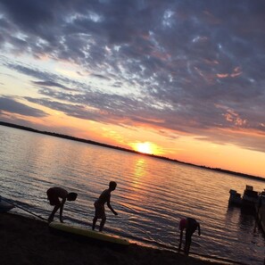 Kids playing on the beach at sunset.