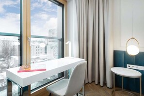 A minimalist bedroom with a comfortable bed, white walls, and a stylish desk by the window, perfect for a work-from-home setup.
