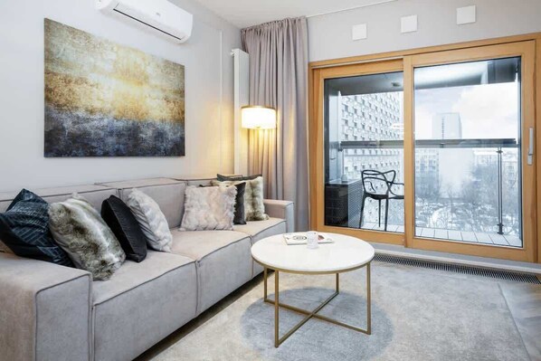 A sophisticated living room with a modern gray sofa, a round marble coffee table, and ambient lighting, providing a cozy yet elegant atmosphere.